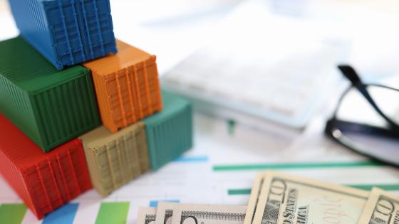 Cargo containers with dollar banknotes and glasses on financial document