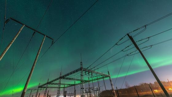 electrical substation and wooden pole power lines under Aurora Borealis