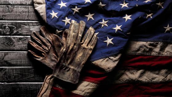 Old and worn work gloves on large American flag 
