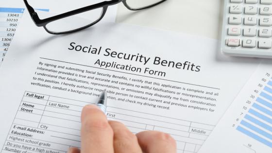 Hand Holding Pen Over Social Security Benefits Form
