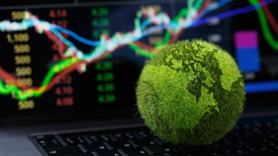 Green Globe on laptop keyboard with Stock graph on the laptop screen