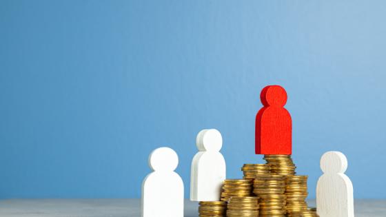 Wooden figures on top of piles of coins