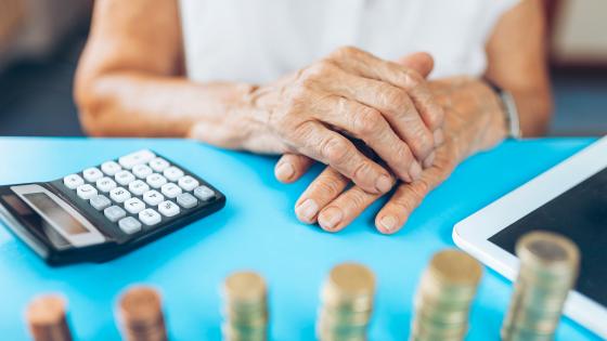 Older woman with calculator and piles of coins