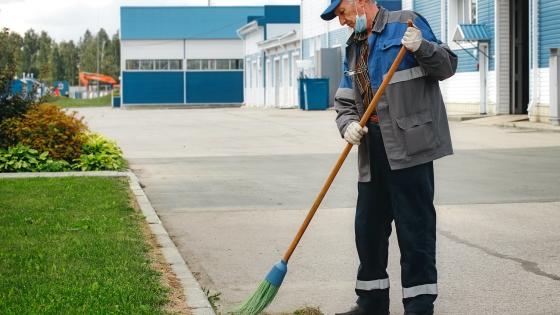 Older man in uniform sweeping