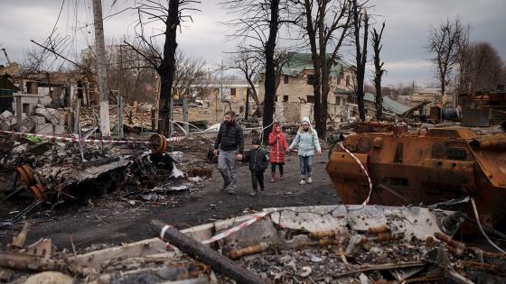 A family walks amid destroyed Russian tanks in Bucha, on the outskirts of Kyiv