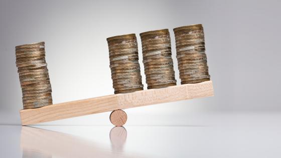 Stacks of coins on wooden see-saw