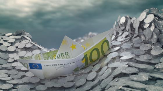 Boat made of euro note on sea of coins