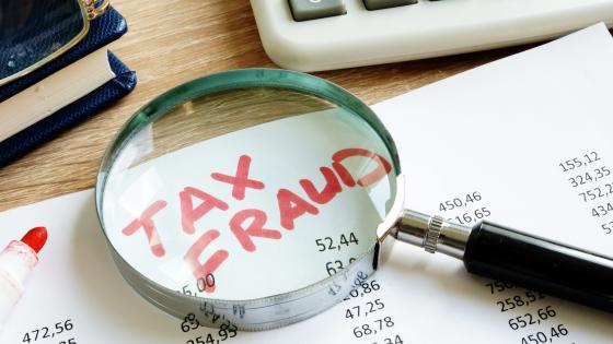 The words "tax fraud" under magnifying glass