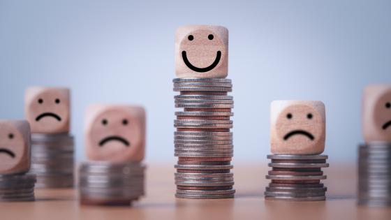 Happy and sad faces on piles of coins 