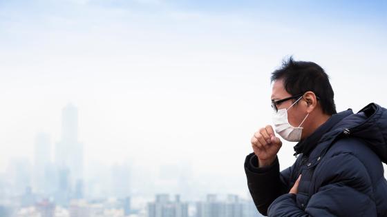 Man in mask coughing due to pollution