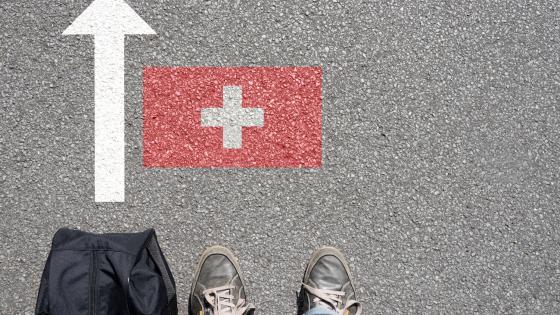 Shoes and bag on floor in front of Swiss flag