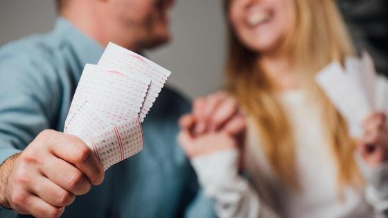 happy couple holding lottery ticket