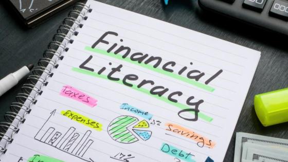'Financial Literacy' is written on a notebook with an array ineligble of graphs and charts