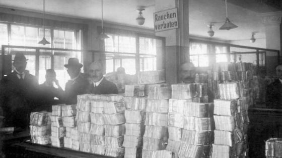 Men stand around huge stacks of money in 1920s Germany