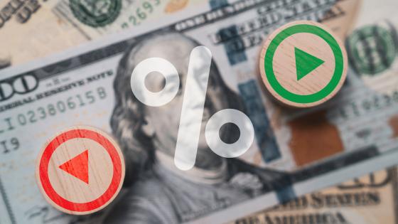 Percentage symbol with up and down buttons on top of dollar bills