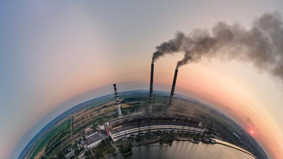 Aerial view from high altitude of little planet earth with coal power plant high pipes with black smokestack polluting atmosphere