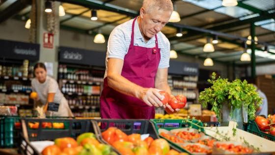 Older worker stacks fruit at a supermarket