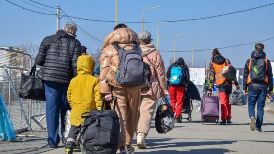 A group of refugees walk down a road with items of luggage