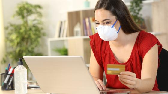 Woman wearing a mask buying something online with a credit card