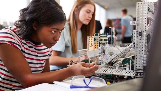 Two Female College Students Building Machine In Engineering Class