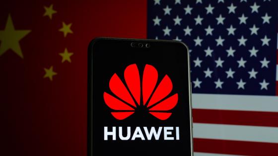 Huawei logo on a smartphone and flags of China and US on a blurred background