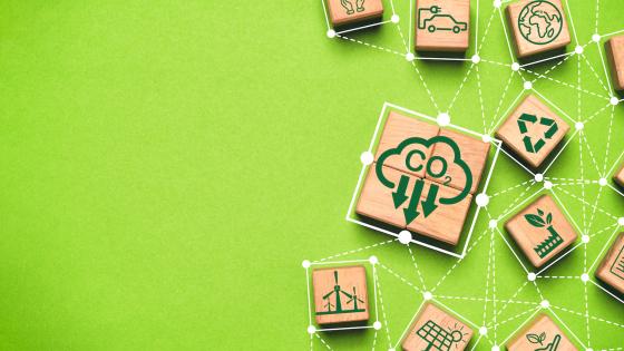 Wooden cubes with emissions reduction icons on green background
