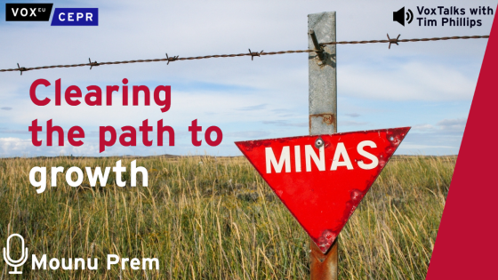 A red triangular warning sign reading "MINAS" attached to a barbed wire fence in a grassy field, with promotional text overlay for "Clearing the path to growth" by VoxEU, CEPR, and VoxTalks with Tim Phillips, interviewing Mounu Prem.